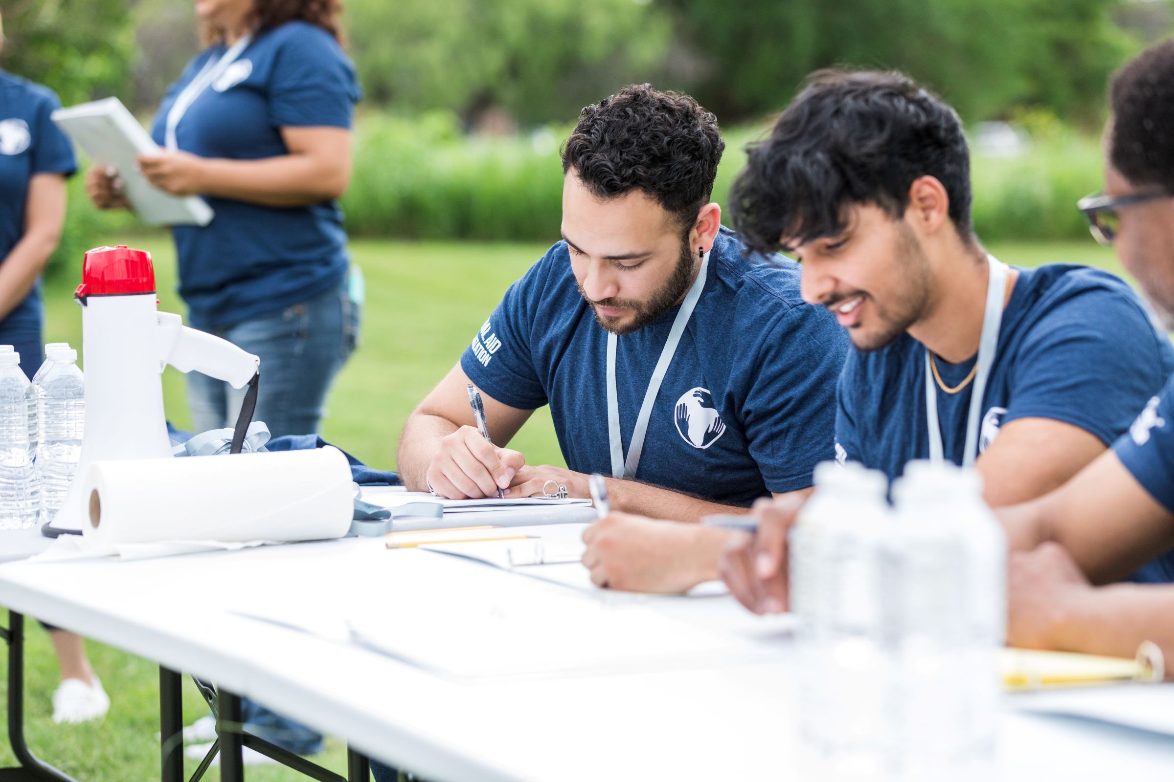 Photo of male students outdoors at a desk working in the field