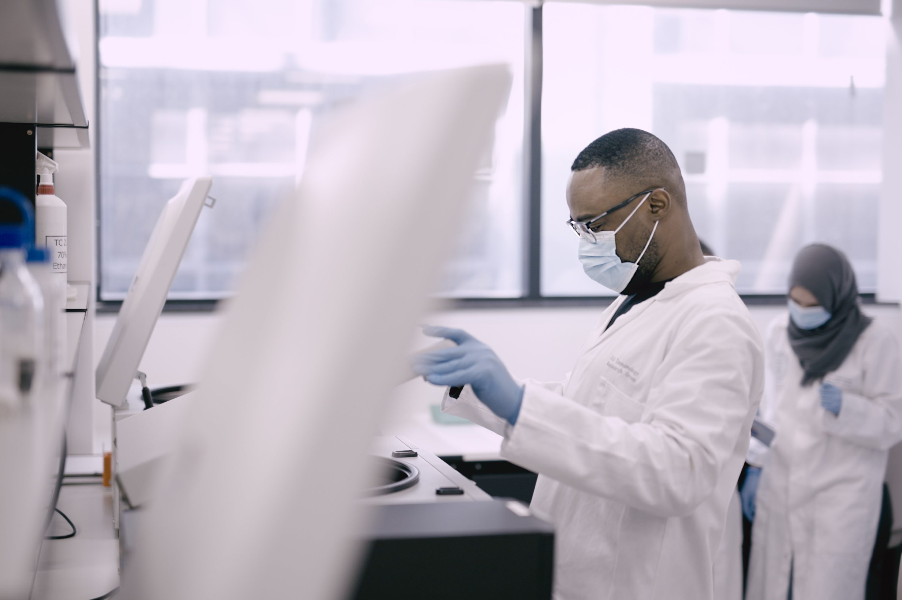 Shot of a young male scientist opening the lid of a piece of scientific equipment