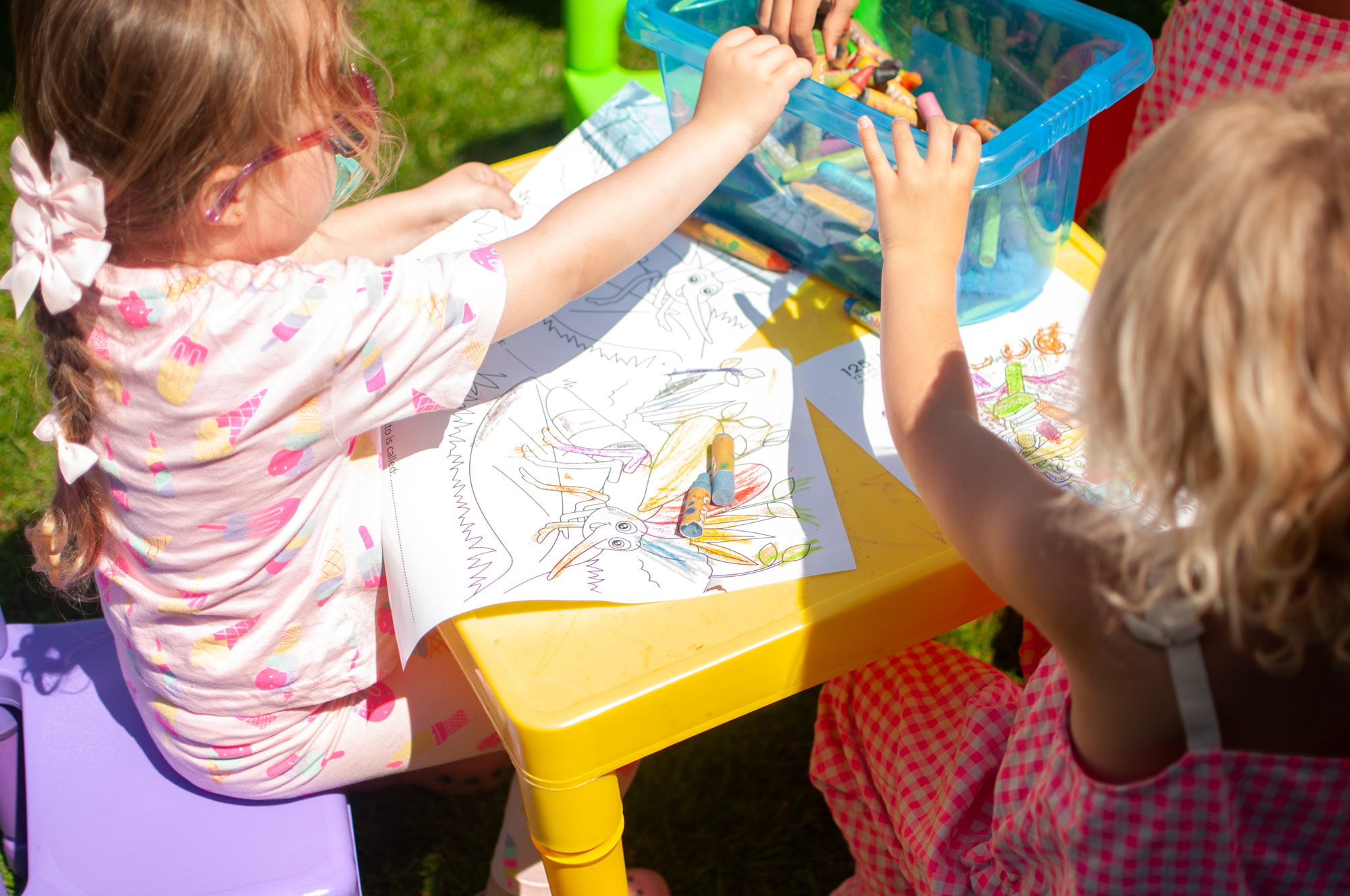 Photo of children at a table using colouring pencils and paper.