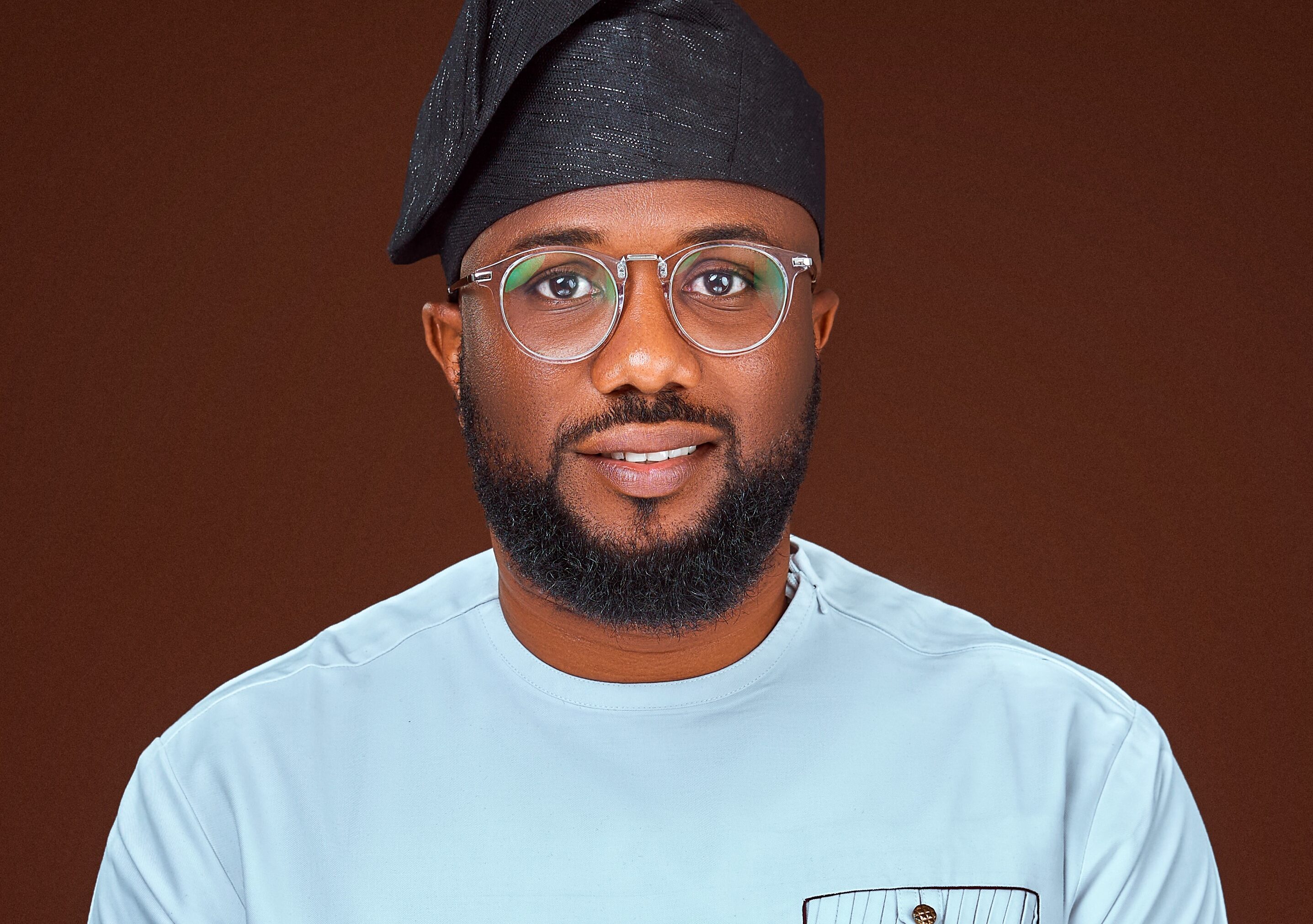 Headshot of Dr Olawale Ogunlade on a dark brown background.
