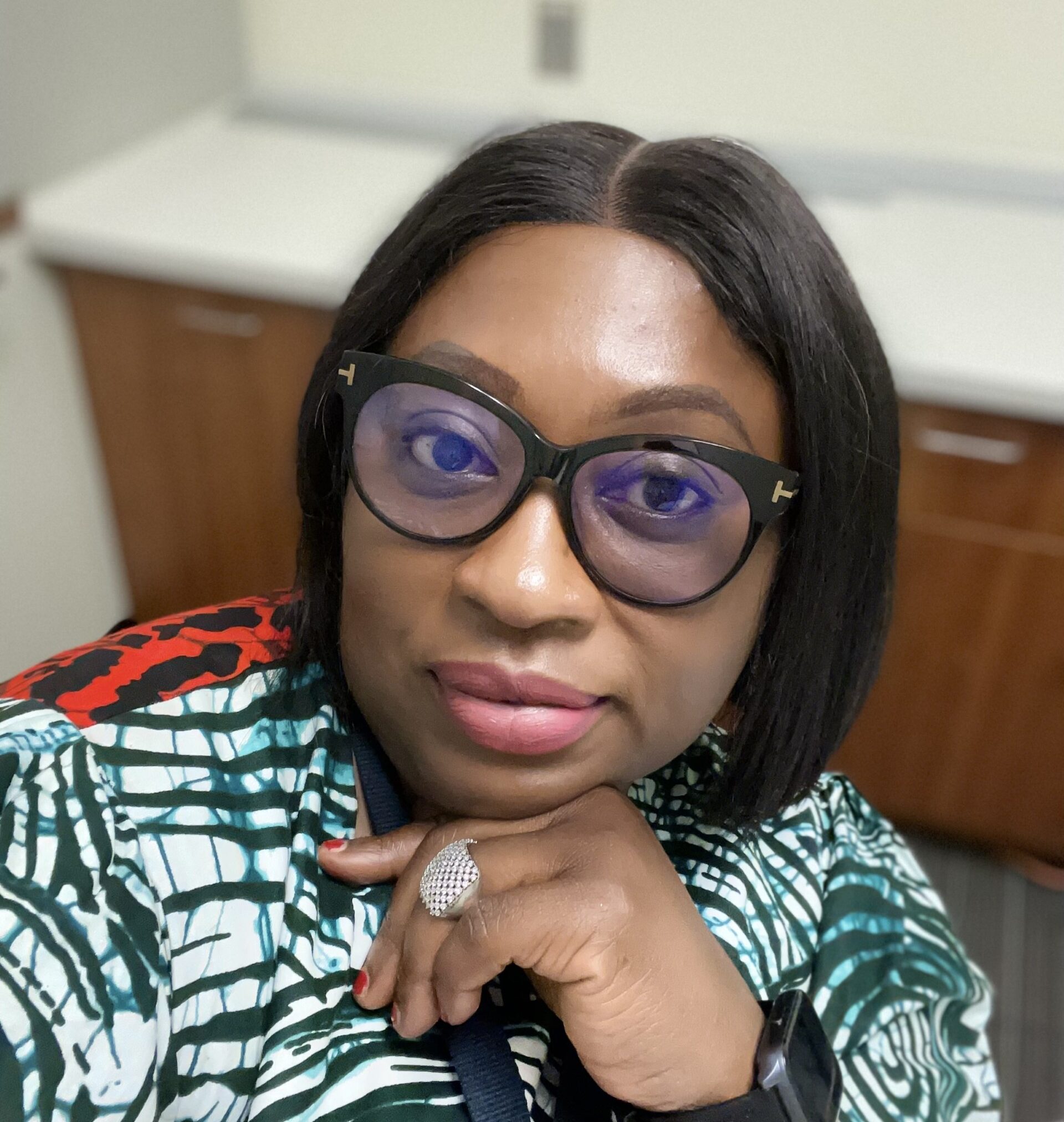 Headshot of Dr Gertrude Odezugo wearing glasses with a black frame and green and white blouse.