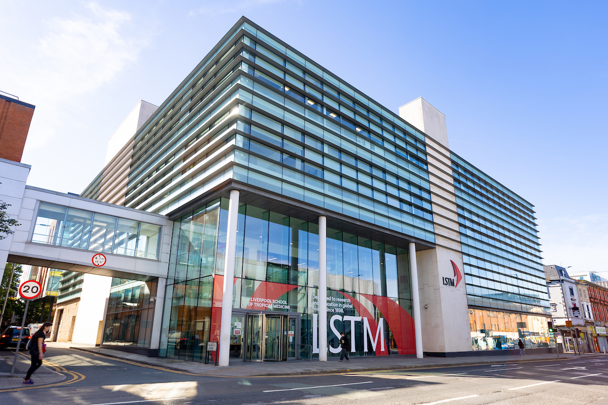 Contemporary glass-fronted building with LSTM signage and a glass entrance at street level, pedestrians nearby.”,