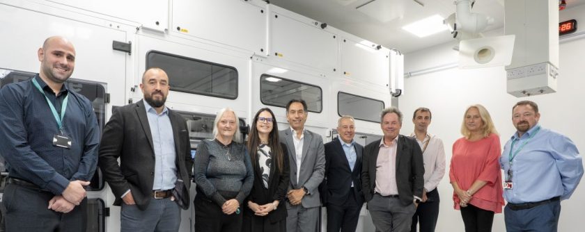 Project leaders gather together in front of lab equipment.